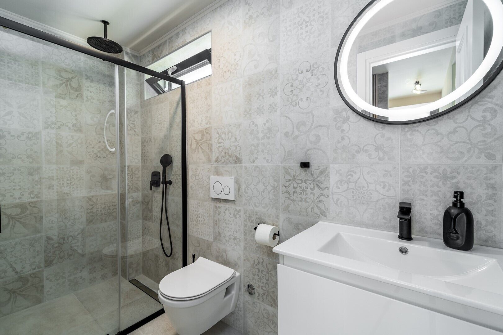A modern bathroom with a glass-enclosed shower, a toilet, a sink, and a mirror.