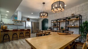 A modern kitchen with a wooden dining table, bar stools, and pendant lighting. - Villa Neven with heated private pool,wine cellar (Seoca)