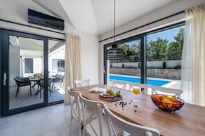Uma sala de jantar moderna com uma mesa de madeira, cadeiras brancas e uma fruteira.