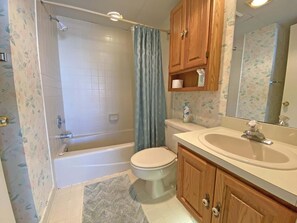 A bathroom with a bathtub, toilet, sink, and wooden cabinets.