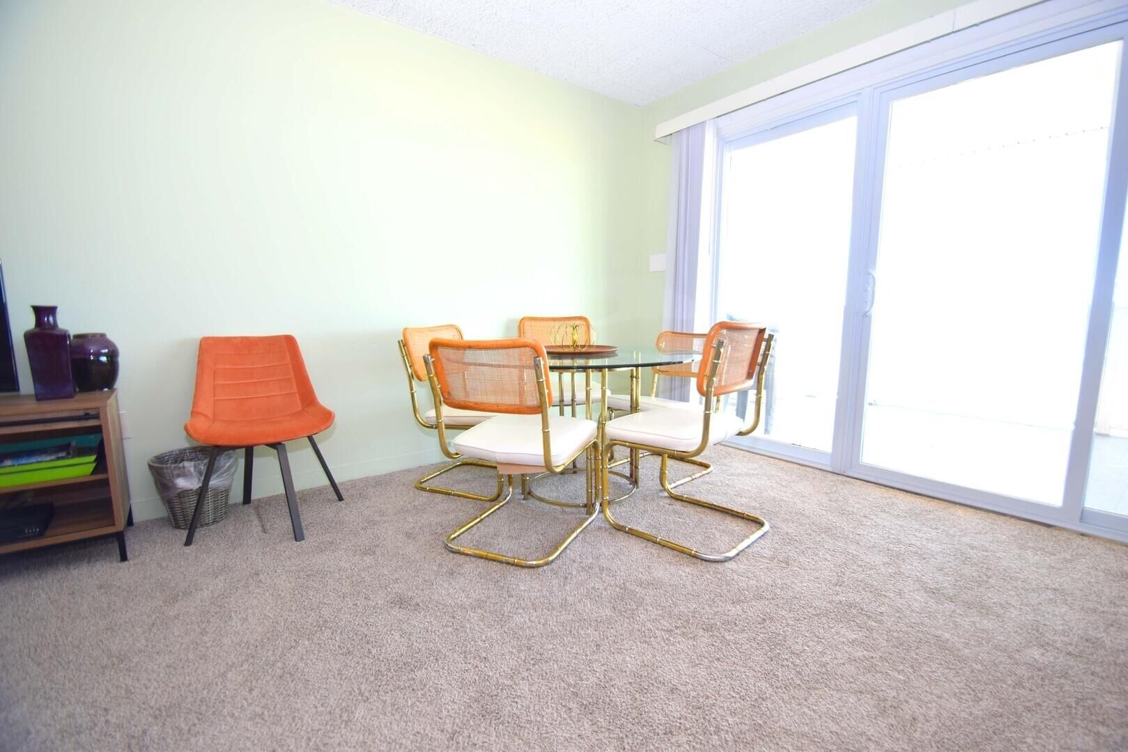 Un coin repas avec une table et des chaises, une bibliothèque et une fenêtre avec des stores.