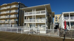 A multi-story hotel with balconies, a wooden deck, and a clear blue sky.