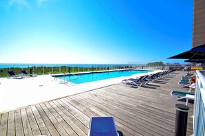 Un espace piscine avec des chaises longues et vue sur l’océan.