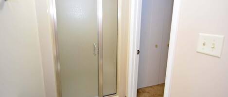 Une salle de bain avec douche, toilettes et une porte donnant sur une autre pièce.