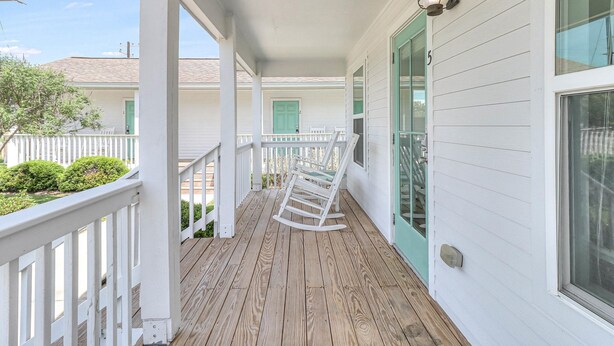 A covered porch with white railings and a wooden deck. - Coast Oaks Cottage 5 1 Bedroom Cottage by RedAwning (Rockport)