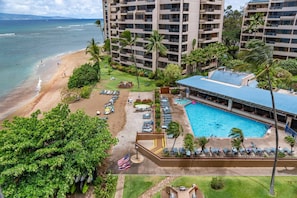 A hotel with a pool, beach, and ocean view.