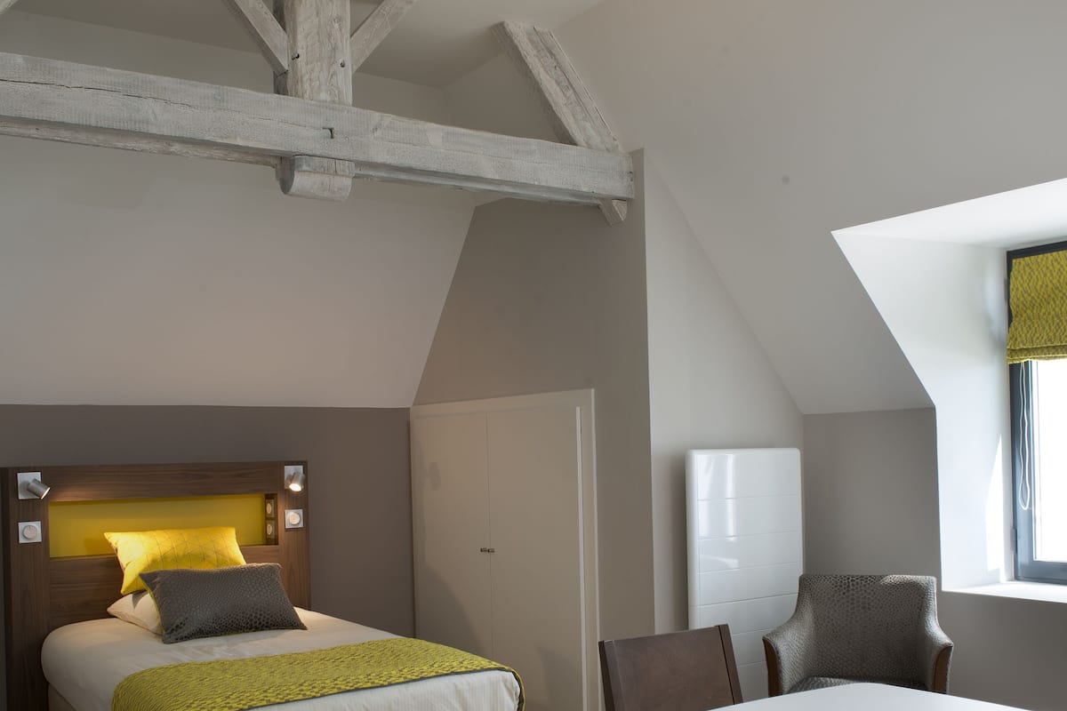 Quarto com cama, mesa de cabeceira e uma cadeira.