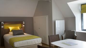 Een slaapkamer met een bed, nachtkastje en stoel.