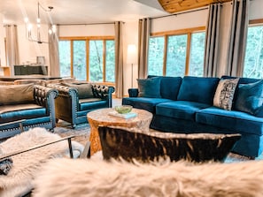 Ein modernes Wohnzimmer mit einem blauen Sofa, einem Ledersessel und einem runden Couchtisch.