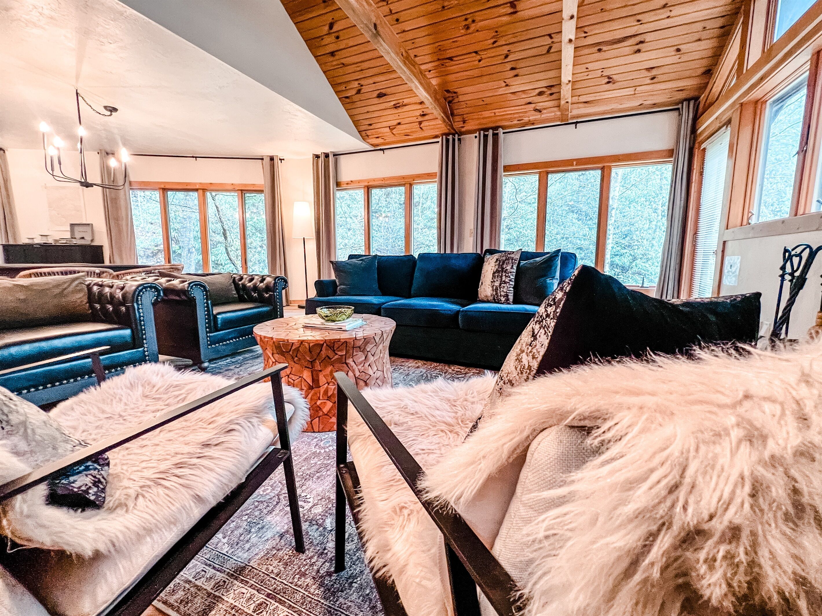 A cozy living room with a blue sofa, a round coffee table, and a fur-covered armchair.