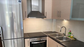 Eine Küche mit Edelstahlgeräten, einem Gasherd, einem eingebauten Backofen, einer Spüle und Holzschränken.