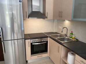 Une cuisine équipée d’appareils électroménagers en acier inoxydable, d’une cuisinière à gaz, d’un four encastré, d’un évier et de meubles de rangement en bois.