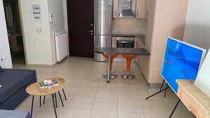 Ein kompakter Wohnbereich mit einer Küchenzeile, einer Essecke mit Tisch und Stühlen, einem Sofa und einem Fernseher.