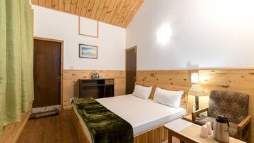 A wooden-paneled room with a bed, a desk, a chair, and a lamp.