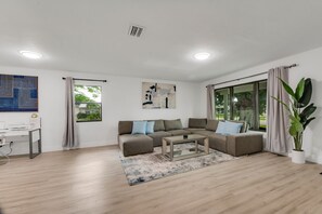 Relax in this stylish living room with a large L-shaped sofa, glass coffee table, and comfortable desk area.
