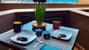 Un tavolo apparecchiato con cibo e bevande su un balcone con vista sul mare.