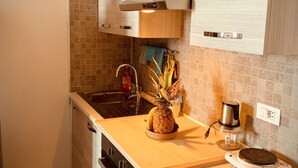 Una cucina moderna con mobili in legno, un lavandino in acciaio inossidabile e un piano di lavoro con ananas e una macchina da caffè.