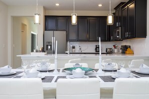Enjoy meals in the kitchen with stainless steel appliances and a dining area set with white tableware.