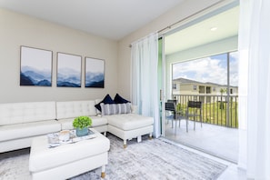 Relax in this stylish living room with a sofa, side table, and potted plant, plus a balcony with a chair and table.