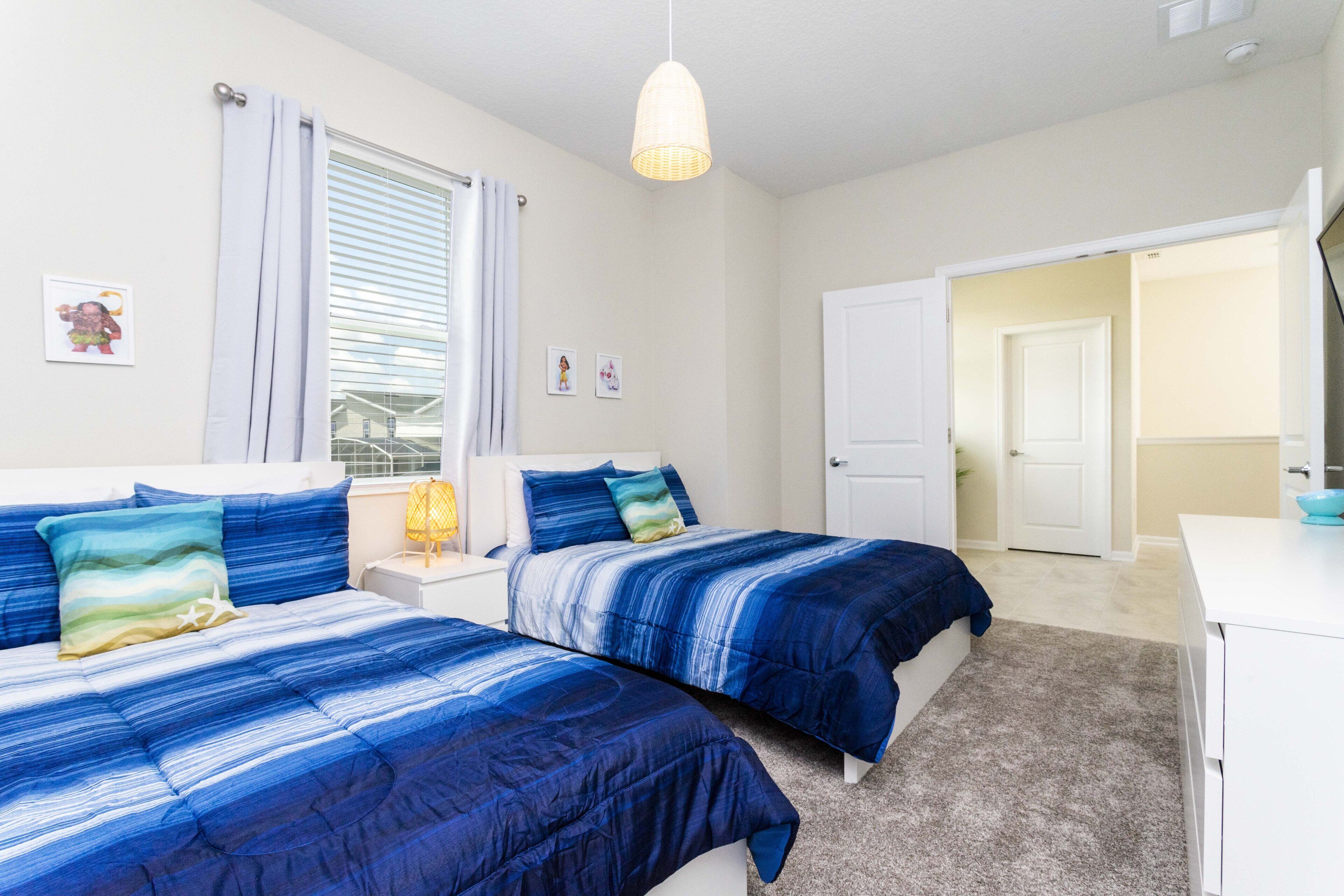 Quarto com duas camas, uma escrivaninha e uma janela com cortinas.