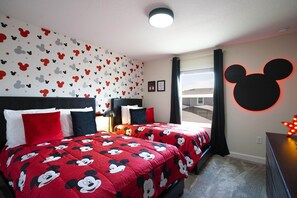 Ein Hotelzimmer mit Bettwäsche und Wanddekor im Mickey Mouse Design, sowie einer sternförmigen Lampendekoration.