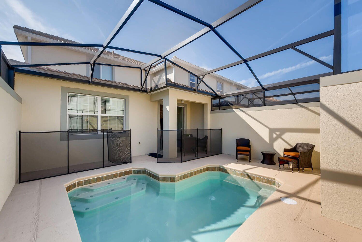 Ein überdachter Außenpool mit Glasveranda, eine Terrasse mit Sitzgelegenheiten und im Hintergrund ein Blick auf das Haus.