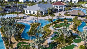 A resort with multiple swimming pools, palm trees, and a building with a red roof.
