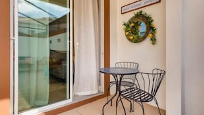 A balcony with a glass door, a small round table, two chairs, a decorative wreath, and a sign that reads "our happy place".