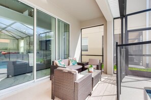 Relax on the balcony with comfortable seating and expansive views of the pool and surrounding greenery.
