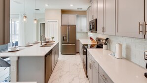 A modern kitchen with a central island, stainless steel appliances, and light-colored cabinetry. - Last Minute Disney Getaway! Luxury Villa with Private Pool & Game Room. Book Now! #43331 (Orlando)