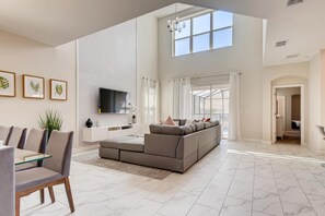 Relax in this spacious living space with a large sofa, flat-screen TV, and dining area.