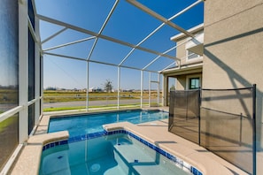 A swimming pool with a clear view of the surrounding landscape, a covered area with a metal railing, and a building with a beige exterior.
