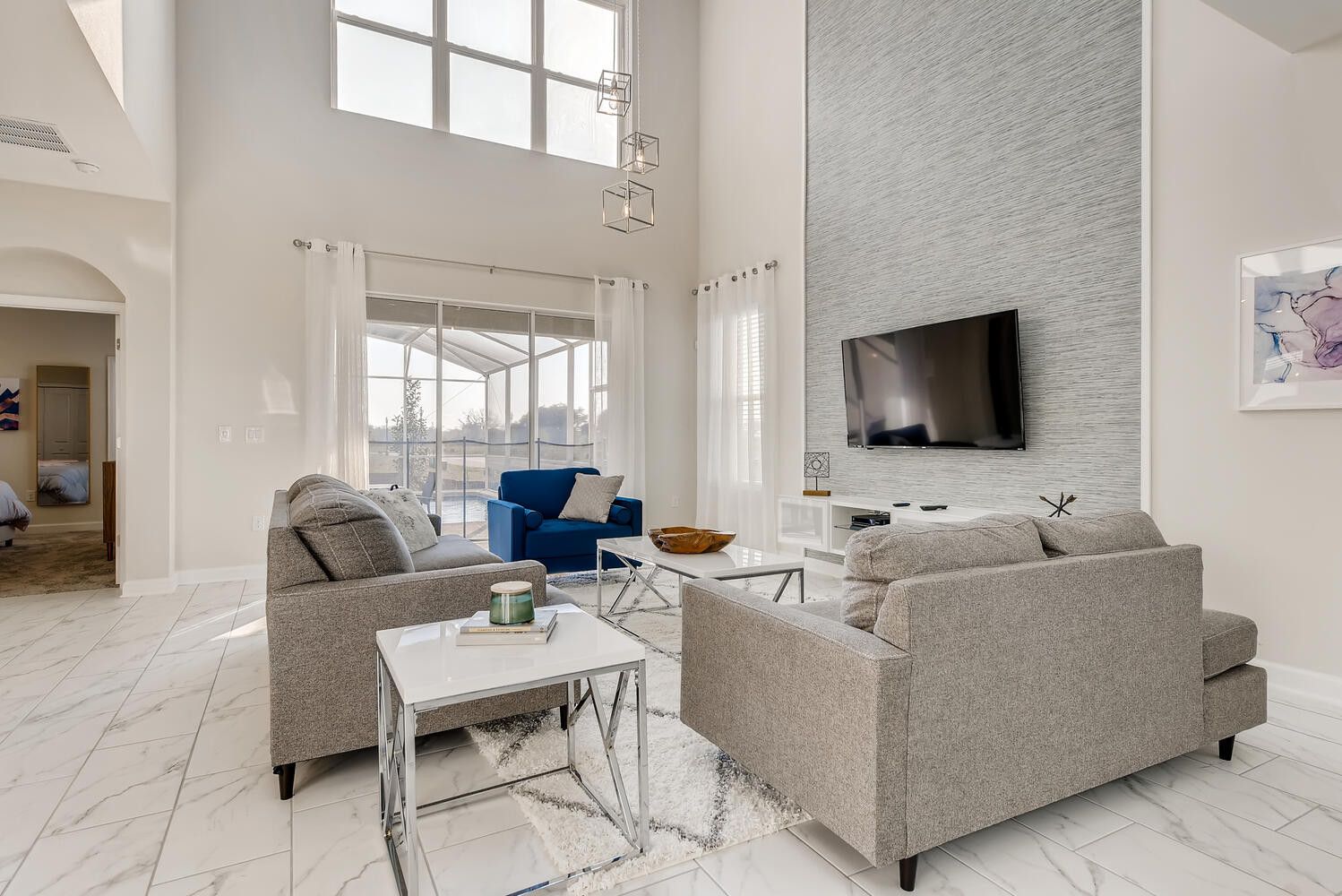 Ein modernes Wohnzimmer mit einem großen Fernseher, zwei Sofas, einem Couchtisch und einer Glastrennwand.
