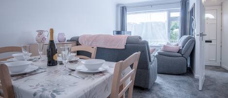 A dining area with a table set for four, a sofa, and a view of the outdoors.