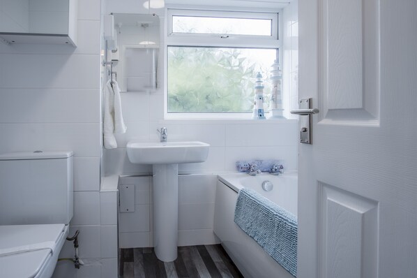 A modern bathroom with a toilet, sink, and bathtub. - Harbour Court - 2 Bedroom - Saundersfoot (Saundersfoot)