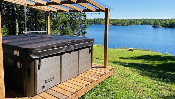 Ein Whirlpool unter einer Pergola mit Seeblick.
