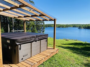 A hot tub under a pergola with a lake view.