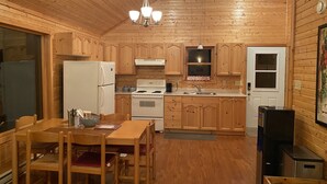 Ein Interieur einer Holzhütte mit Küche, Essbereich und einer kleinen Wohnstube.