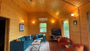 Ein gemütliches Blockhaus-Interieur mit Holzwänden, einem Deckenventilator, einem Fernseher und einem Sofa.