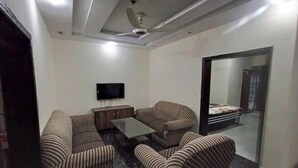 Una sala de estar moderna con sofás a rayas, una mesa de centro, un televisor y un ventilador de techo.