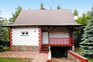 Un bâtiment à deux étages, doté d’un balcon rouge, d’une antenne parabolique et de fondations en pierre.