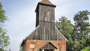 Una iglesia de madera rústica con un alto campanario y una entrada de ladrillo.