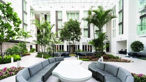Un patio intérieur moderne, doté d’un espace de détente central, entouré de verdure et d’une architecture contemporaine.