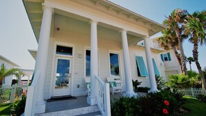 A two-story house with a porch, white columns, and a white picket fence. - Seaglass Cottage Brand New Cottage located within The Shores, just a short walk to the beach! (South Padre Island)