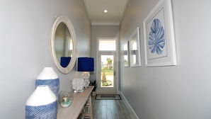 A hallway with a wooden bench, a mirror, and framed artwork on the walls. - Seaglass Cottage Brand New Cottage located within The Shores, just a short walk to the beach! (South Padre Island)