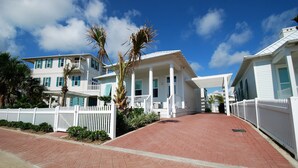 A coastal property with a paved walkway, white fences, and a clear blue sky. - Seaglass Cottage Brand New Cottage located within The Shores, just a short walk to the beach! (South Padre Island)