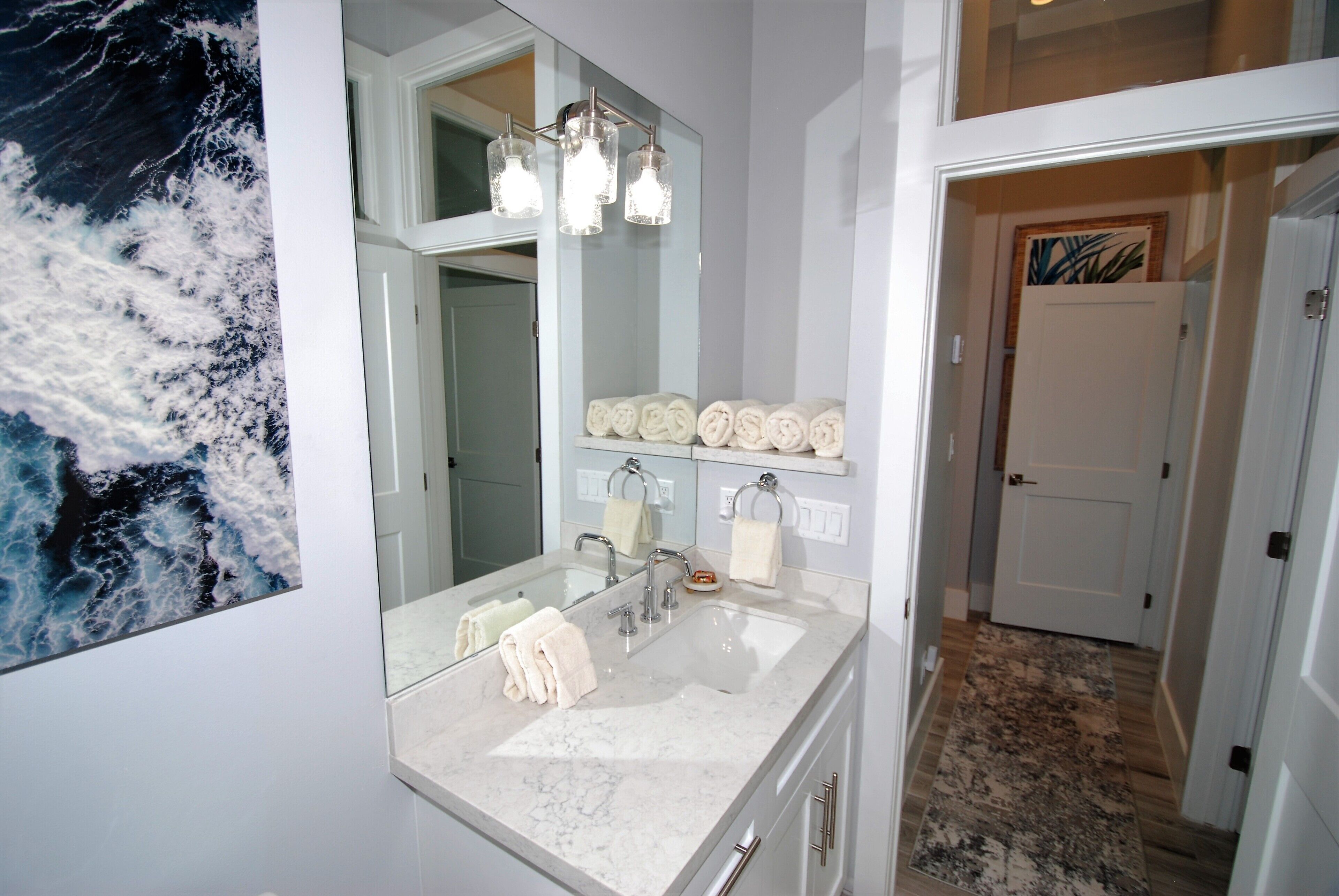 Une salle de bain avec un grand miroir, un lavabo et un porte-serviettes.