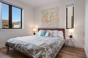 Relax in a spacious room with a large bed, wall art, and a window offering a view of the outside.