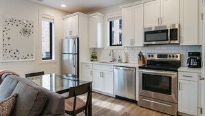 Una cucina moderna con mobili bianchi, elettrodomestici in acciaio inossidabile e un tavolo da pranzo in vetro.