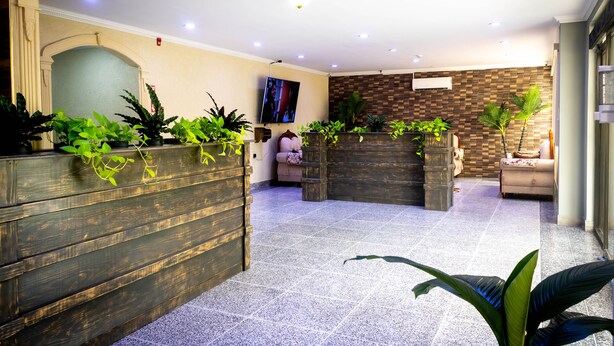 A lobby with wooden planters, a television, and a tiled floor. - Crown Hotel Piarco (Piarco)